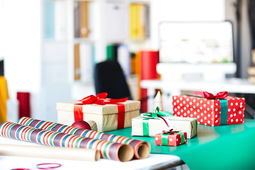 Group of packed gifts in boxes and rolled wrapping paper on table in studio