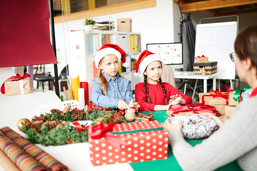 Two pretty siblings in xmas attire talking to mom while preparing gifts for their friends