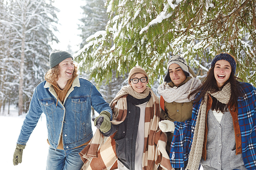 Group of happy young people running towards camera in winter enjoying time in Christmas vacation