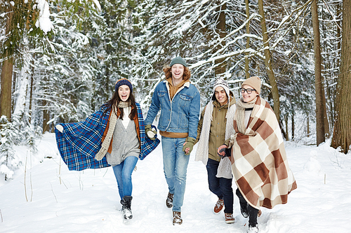 Full length portrait of modern young people walking towards camera in winter resort and laughing happily