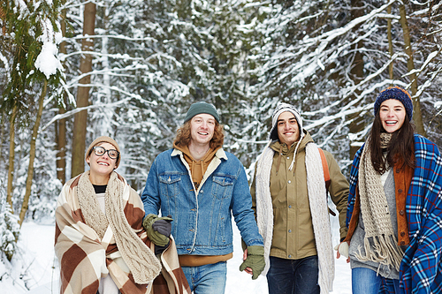 Waist up portrait of modern young people walking towards camera in winter resort and laughing happily