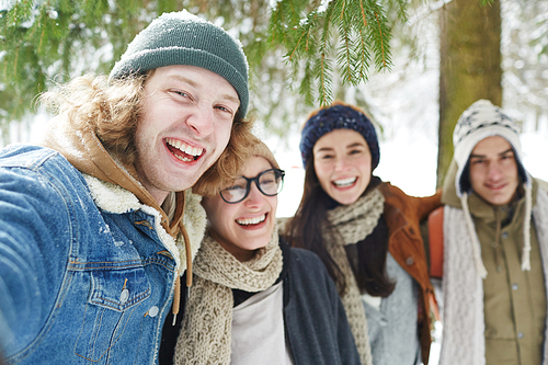 Portrait of four happy young people enjoying time in winter resort and laughing merrily , focus on man in front