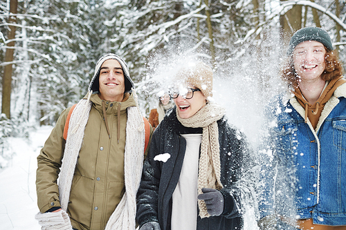 Waist up portrait of happy young people running towards camera while having fun in winter forest during vacation