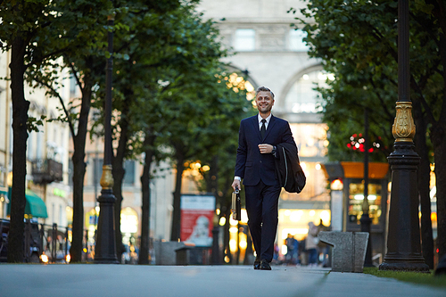 Successful businessman in suit going down central street of modern city