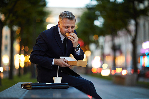 Hungry man in suit eating his sandwich in hurry during short break between parts of business conference