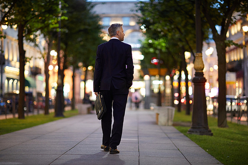 Back view of contemporary businessman going along central street after work