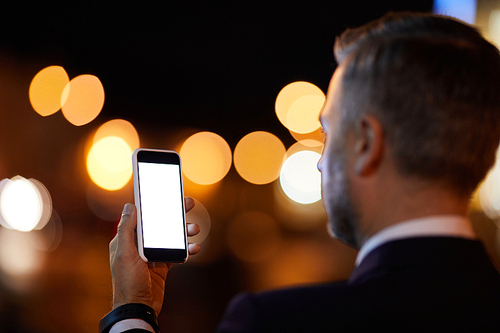 Modern businessman making selfie on his smartphone during night chill in the city