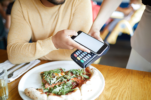 Appetizing pizza on plate and young man paying for it through mobile app in his smartphone