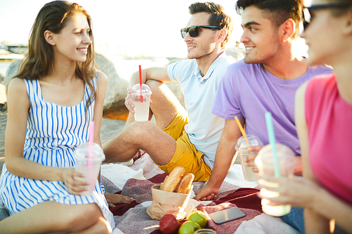 Group of teens having picnic on the beach on hot summer day during summer vacation