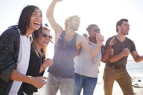 Group of multiracial young people laughing while having fun during party on beach.