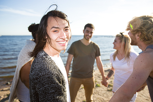 Attractive Asian man cheerfully smiling and  while spending time with friends on beach party.