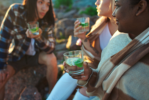 Group of young diverse people enjoying cold drinks while spending time together during nice multiethnic party.