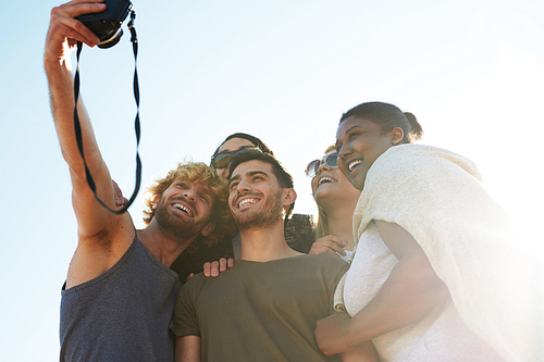 Guy with photocamera making selfie with friends on sunny day in summer
