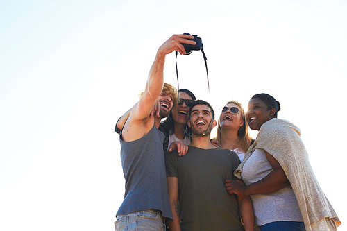 Ecstatic young friendly people making selfie on photocamera against sunshine