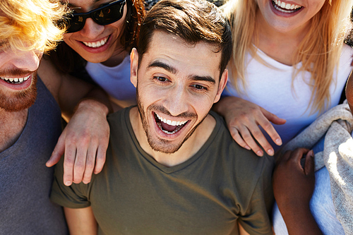 Excited guy and his friends enjoying summer day or vacation on the beach