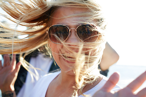 Happy blonde in sunglasses  while enjoying beach dances