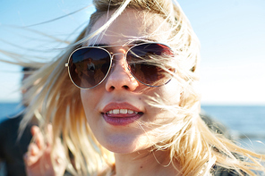 Pretty girl in sunglasses  while spending summer weekend on the beach