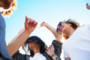 Happy young people dancing on summer weekend under blue sky on sunny day