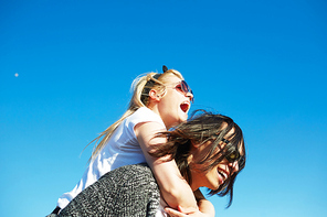 Ecstatic girl embracing her boyfriend while lying on his back against blue sky