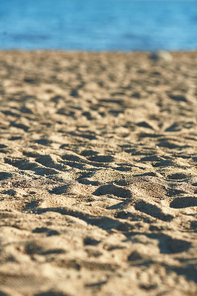 Sandy dunes on beach with blue water on background on hot summer day