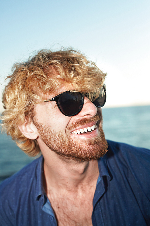 Smiling guy with blond wavy hair wearing shirt and sunglasses