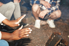 Hands of African-american woman close to campfire on summer evening