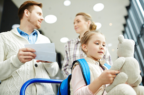 Cute little girl with backpack playing with teddybear while on travel with her parents