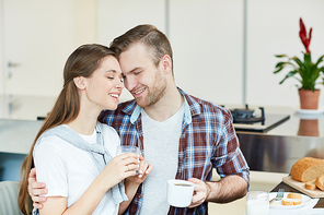 Young affectionate married couple taking pleasure in being together during breakfast