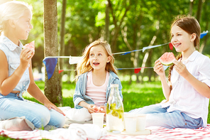 restful kids eating water- at picnic on green lawn on weekend