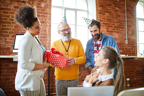 Three cheerful employees congratulating their colleague on birthday in office