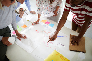 Business people standing around meeting table and analyzing business plan together at the table