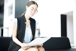 Young serious businesswoman concentrating on paperwork and reading document