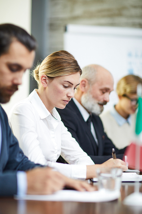 One of delegates making notes at working conference among her foreign colleagues