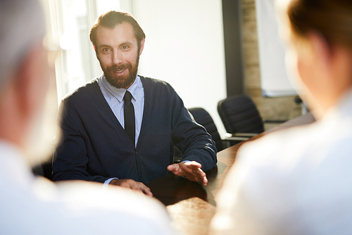 Young confident man talking to employers and answering their questions about himself