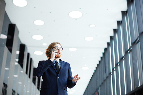 Mobile business agent in suit speaking to client on smartphone in airport