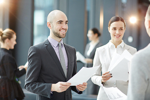 Happy young traders with business documents consulting one of clients at meeting