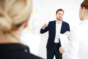 Confident businessman explaining his working idea while discussing plans with colleagues at meeting