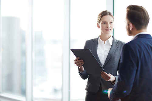 Young elegant employees discussing document or contract and its points at meeting in office