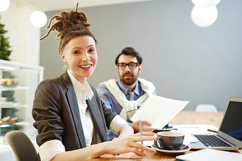 Successful young businesswoman with dreadlock bun on head  by her workplace