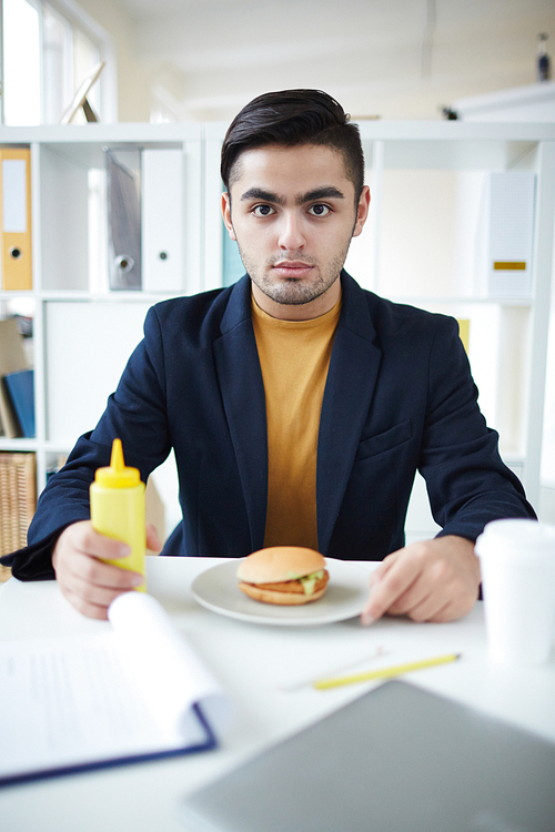 Hungry businessman with mustard and hamburger  while going to eat the snack