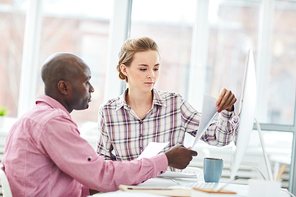 Intercultural office managers or economists reading financial documents at meeting