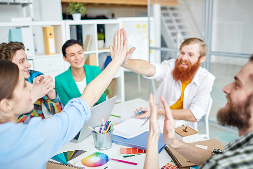 Colleagues giving five at the table during a business meeting