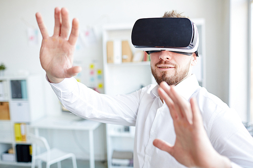 Businessman  in virtual reality glasses orienting in space at office