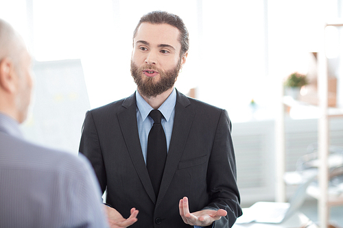 Young bearded businessman discussing his ideas with his partner at office