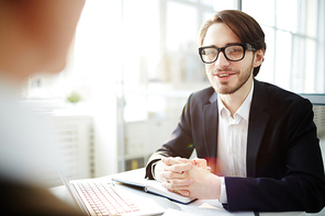 Businessman in eyeglasses having discussion with his colleague during working day