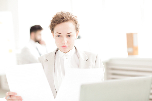 Businesswoman working with documents. Young businesswoman examining documents at office