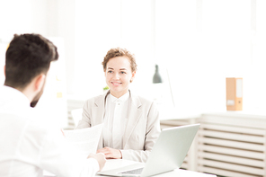 Smiling businesswoman communicating with her colleague at the table at office