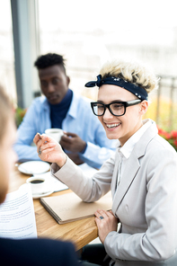 Cheerful young employee laughing during conversation with colleague about plans for new working year