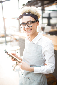 Young waitress or owner of restaurant with notepad and pen waiting for new clients