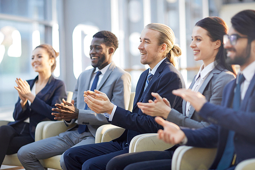 Row of business people clapping hands after report of speaker